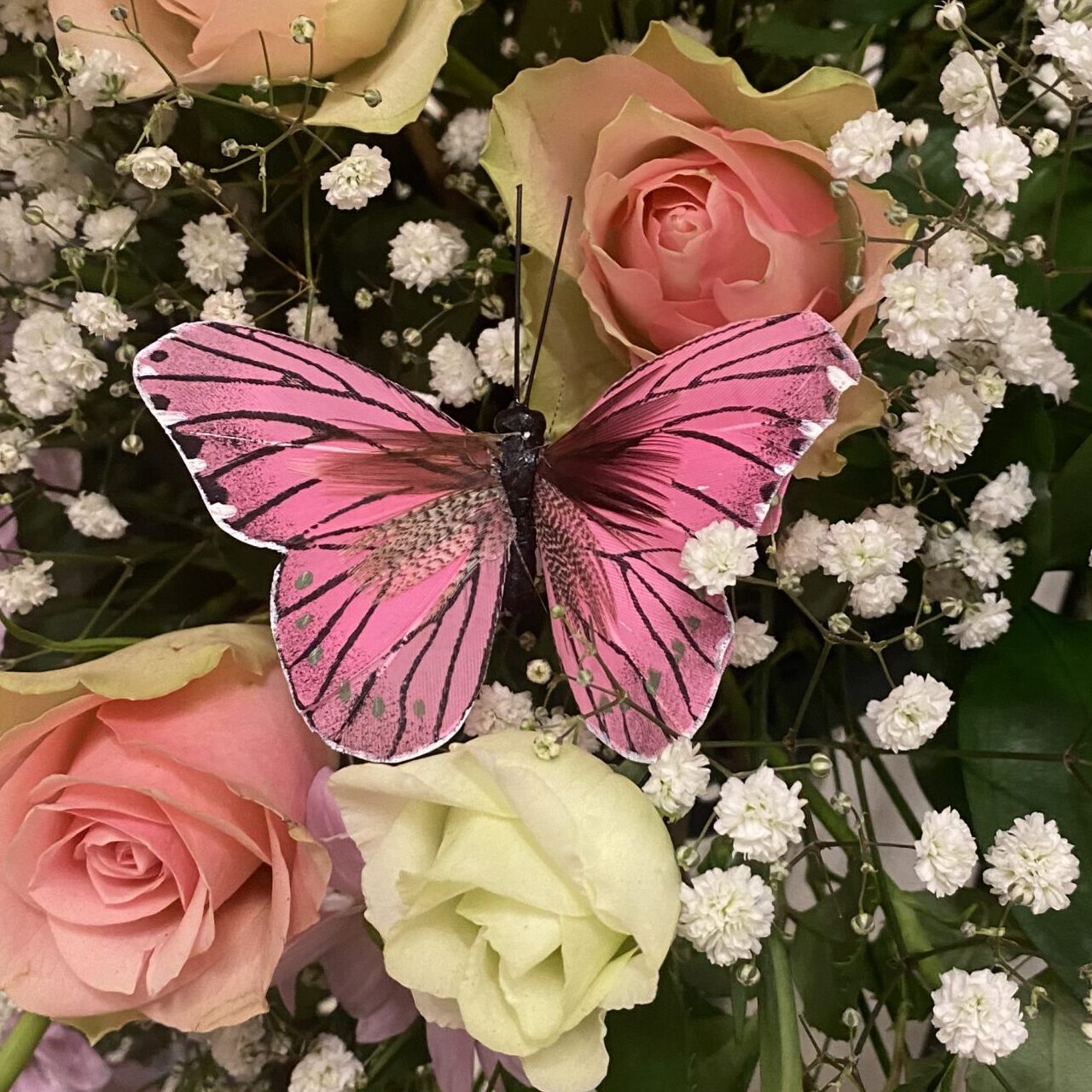 En fjäril som sitter bland begravningsblommor vid en personligt avsked