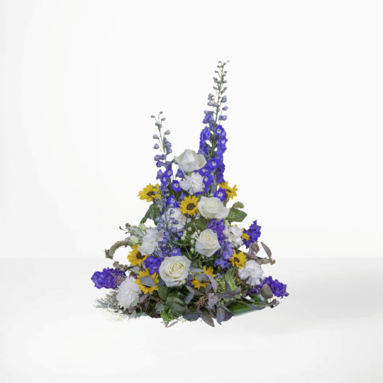 Sorgdekoration med blå riddarsporrar, gula solrosor och vita rosor – en symbol för hopp och frihet vid begravning.