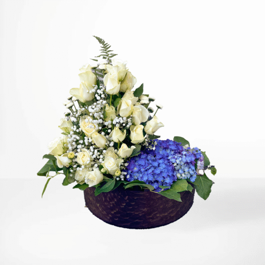 Sorgdekoration formad som en segelbåt med vita rosor som segel och blå hortensia som havet – en symbol för frihet och resan vidare.