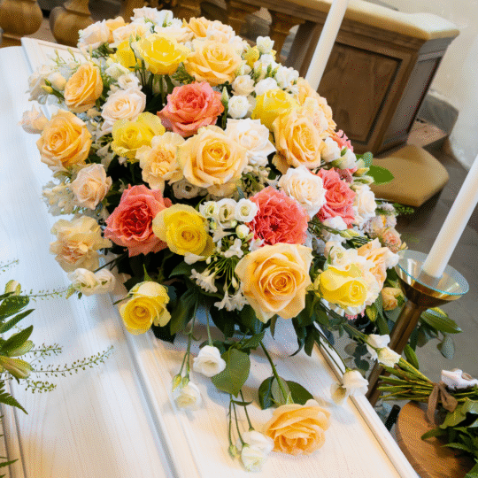 Kistdekoration med rosor i nyanser av gult, aprikos, rosa och vitt